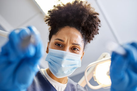 Confident Dentist in Medical Mask Examining a Patient With Professional Toolsの写真素材
