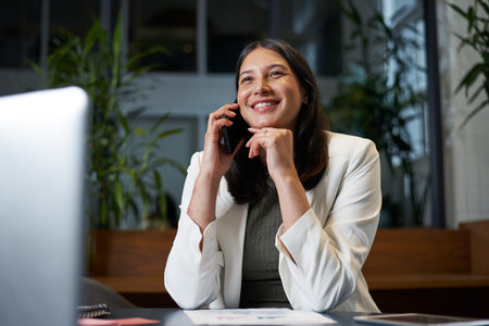 Confident Businesswoman on Phone Call During Work in Modern Office Environmentの写真素材