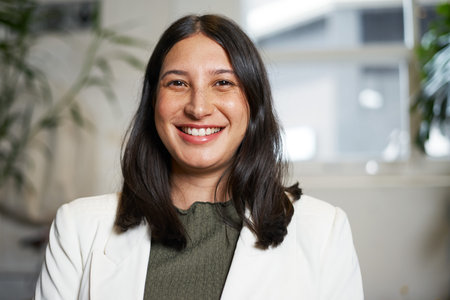 Friendly Professional Woman Smiling in Office Environment with Plant Background