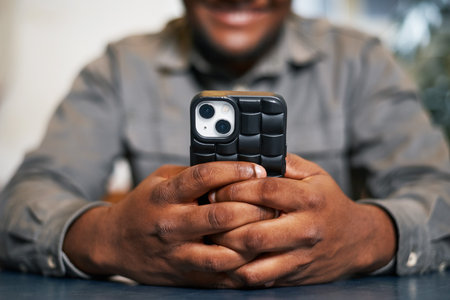Person Holding Smartphone with a Stylish Black Case in a Relaxed Settingの写真素材