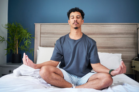 Man Meditating on Bed in Calm Atmosphere with Health and Relaxation Focusの写真素材