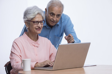 Senior couple looking at laptop and pointing at screen
