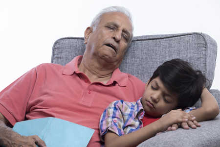 Grandfather and grandson sleeping on sofaの写真素材