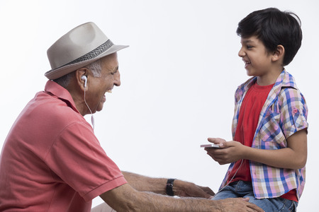 Grandfather and grandson listening musicの写真素材