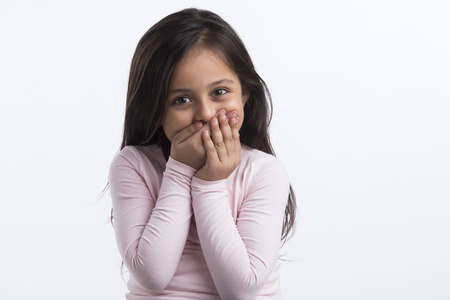 Little  girl laughing by putting her hands on her mouth.の写真素材