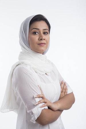 Portrait of woman wearing white head scarf standing arms crossedの写真素材