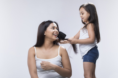 Little girl combing mothers hairの写真素材