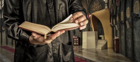 Koran with muslims man . Mosque background . Koran - holy book of Muslimsの写真素材