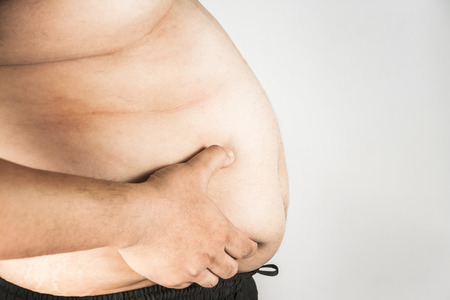 Overweight man body with hands touching belly fatの写真素材