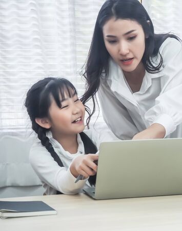 Young women and children are using computers.happy enjoy in the living room at home. family activity concept.の写真素材