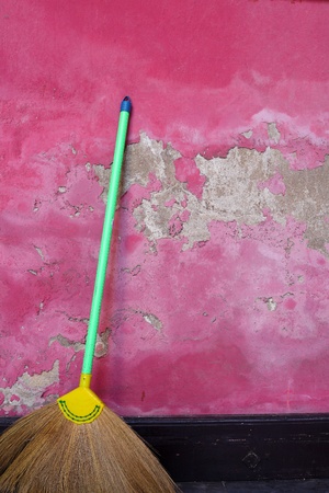 Broom leaning against a grunge pink wallの写真素材
