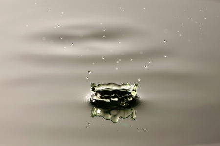 A drop of water that have a green in water spread.の写真素材