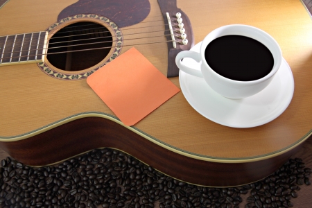 The Concepts that White coffee cup and Notebook paper orange resting on guitar.の写真素材