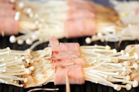 Flammulina Velutipes Mushrooms and bacon on grill is domestic food,Thailand 