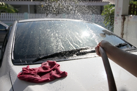 White car washing Front windshield with Water hose in house.