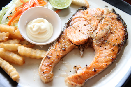 grilled salmon steak with french fries and toast on the table in restaurant.の写真素材