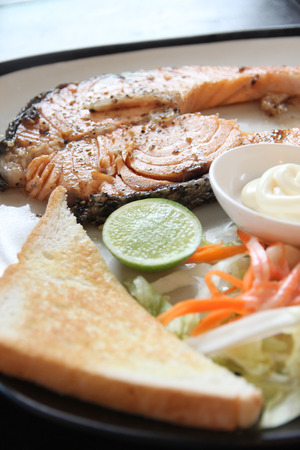 grilled salmon steak with french fries and toast on the table in restaurant.の写真素材
