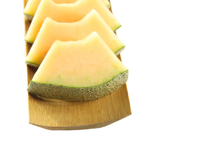 Cantaloupe melon cut into slices isolated on bamboo dish.の写真素材