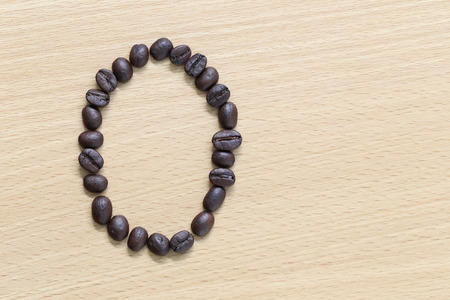 Coffee beans of alphabet placed on the wood .