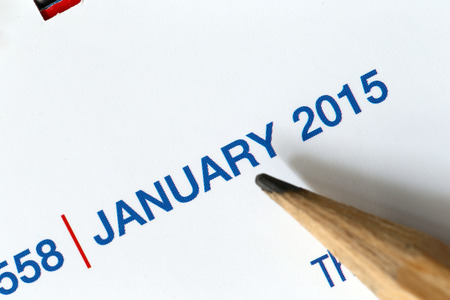 The tip of a pencil point to the year 2015 text on a calendar.