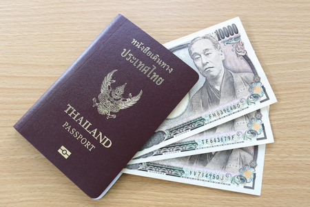 Banknotes of Japan in thai passport on wood background.の写真素材
