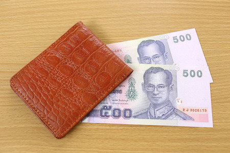 Banknotes of Thailand in wallet on wood background.