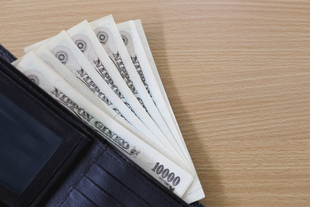 Banknotes of Japan in wallet on wood background.