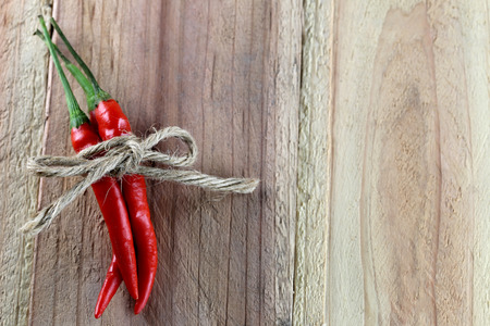 Red peppers tied with hemp rope on the wood background.の写真素材
