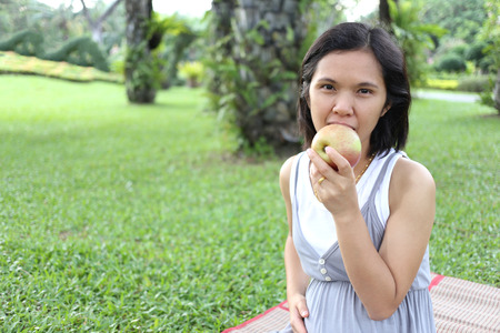 Thai pregnant mom to eat apple in the garden for healthy full strength.の写真素材