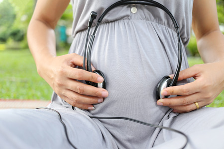Pregnant women put earphone in hand on her belly for development of hearing to baby.