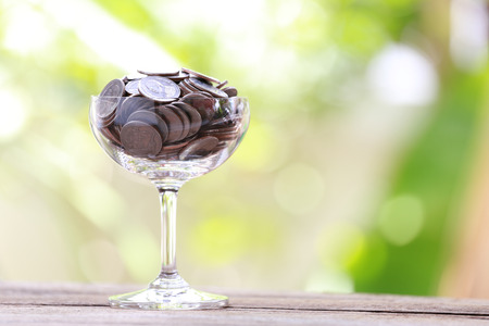 silver coin in glass is placed on a wood floor with colorful bokeh background for business concept image.の写真素材
