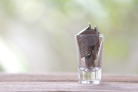 silver coin in glass is placed on a wood floor with colorful bokeh background for business concept image.の写真素材