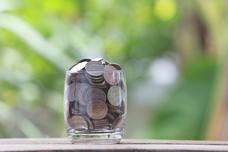 silver coin in glass is placed on a wood floor with colorful bokeh background for business concept image.の写真素材
