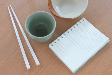Tile bowl and white chopsticks wooden placed beside the book on a wood background,for design of foods concept.の写真素材
