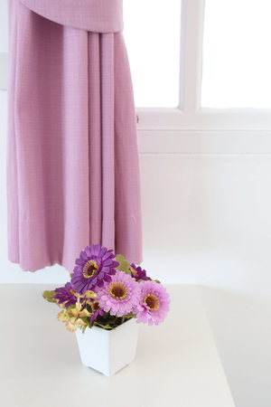 Vintage pink artificial flowers on a table in the white bedroom interior concept for design the background.の写真素材