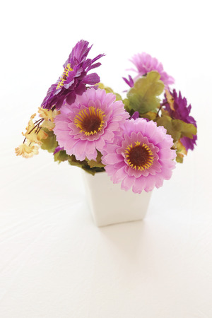 Vintage pink and violet artificial flowers on a white fabric in the bedroom interior concept and design.の写真素材