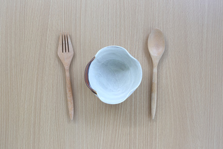Wooden spoon,fork and white cup in top view on wood background for design concept food.
