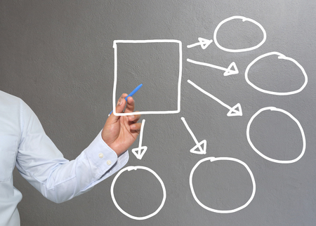 Hand of businessman drawing graphics a symbols geometric shapes graph to input information concept of investment profit in business or management system and have Gray wall of background.の写真素材