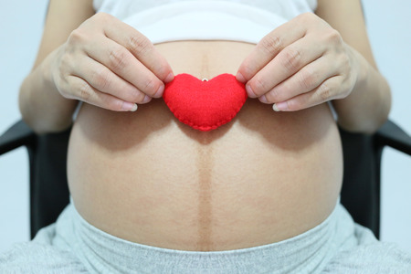 Red heart symbol in hand a asian women pregnant in concept of love for the infant.の写真素材