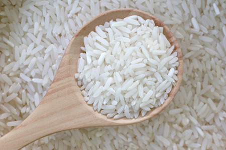 Organic jasmine rice in wooden spoon on pile grain rice for nature food background.の写真素材
