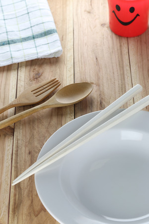 White plate,wooden spoon and chopsticks on wooden floor background.の写真素材