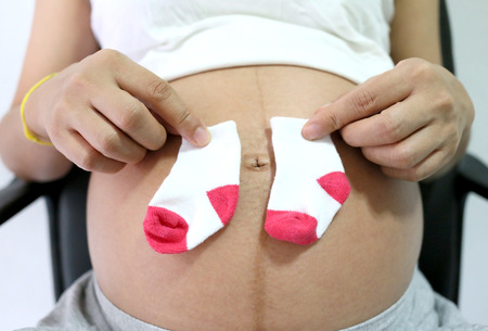 Pregnant women keep sock placed on belly concept of love for the baby.の写真素材