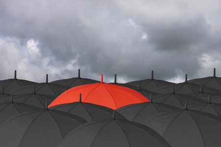 Red umbrella and Surrounded by a black umbrella,concept for management business idea on rain cloud background.の写真素材