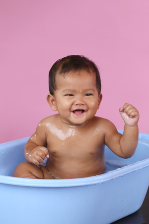 Asian baby bathing in a blue swimming pool with happily,concept of health and cleanliness of the children.の写真素材