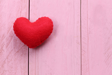 Red heart is placed on a pink wooden floor concept of love in Valentine's Day.の写真素材