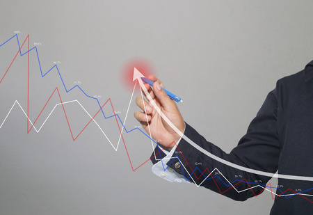 Hand of businessman use a blue pen point to top white arrow of grow graph in concept of investment and business profits on gray background.の写真素材