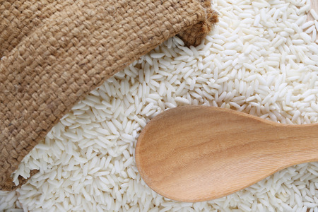 Wooden spoon of empty and hemp sack on organic white rice, glutinous rice or sticky rice for design nature foods concept.の写真素材