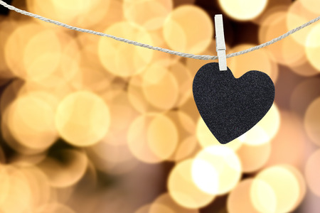 Black Heart hung on hemp rope on abstract colorful bokeh background and have copy space to manage the text you want.の写真素材