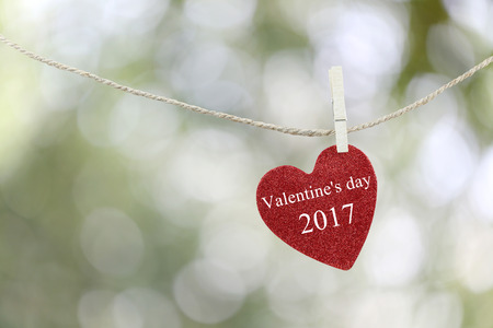 Red Heart hung on hemp rope and have text Happy Valentine's Day 2017 on abstract boken background.