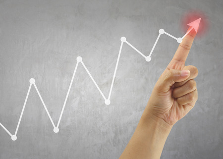 Finger of Businessman touch line graph business in peak point,concept of business investment and profits and assessed.の写真素材